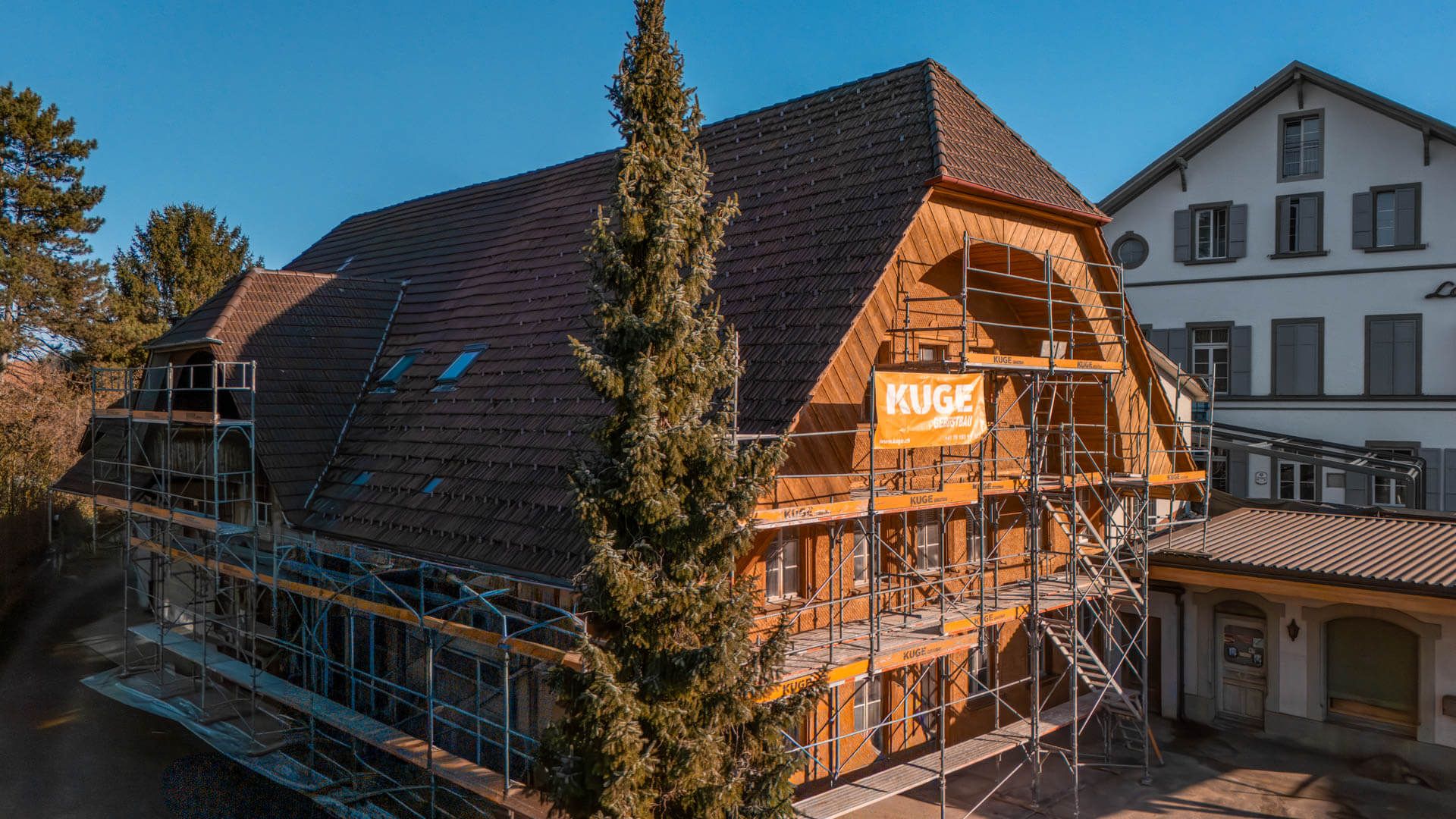 Fassadengerüst mit Treppenturm an einem historischen Holzbau während der Fassadensanierung – Foto: KUGE Bau AG